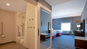 Hotelkamer met douche, bed, bureau en groot raam.