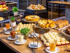 A buffet with various food items, including bread, pastries, and desserts.