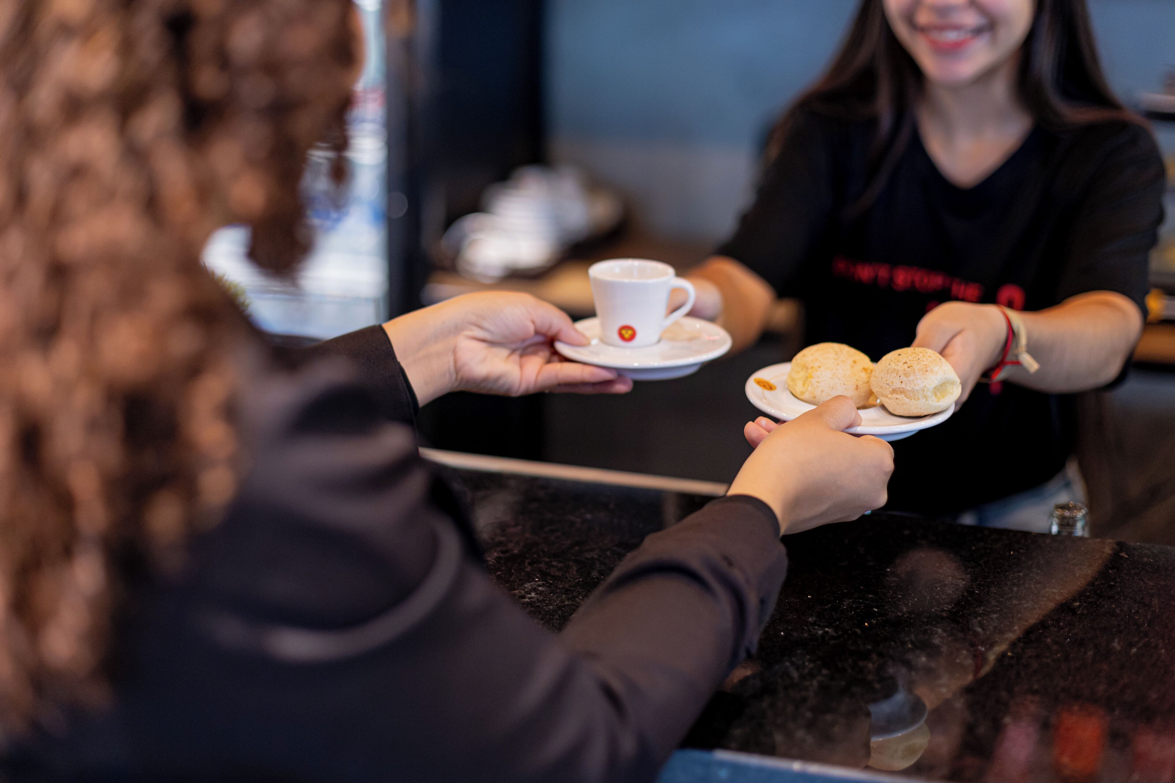 Une personne tenant une tasse et une assiette sur lesquelles se trouvent deux pâtisseries.