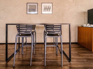 Un comedor con una mesa y sillas, dos cuadros en la pared y un aparador de madera con objetos encima.