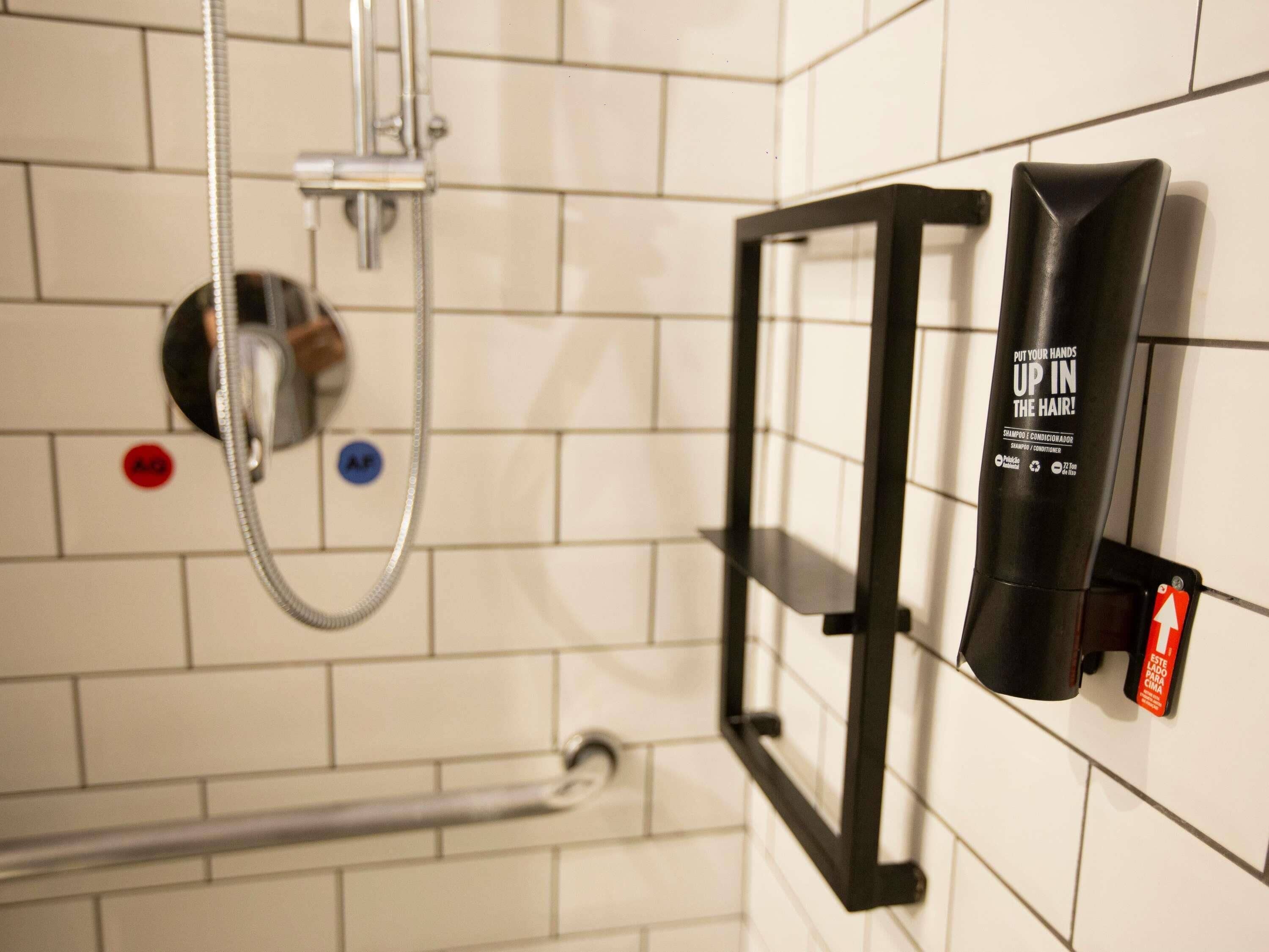 Une salle de bain avec une douche, un porte-serviettes et un flacon de shampoing.