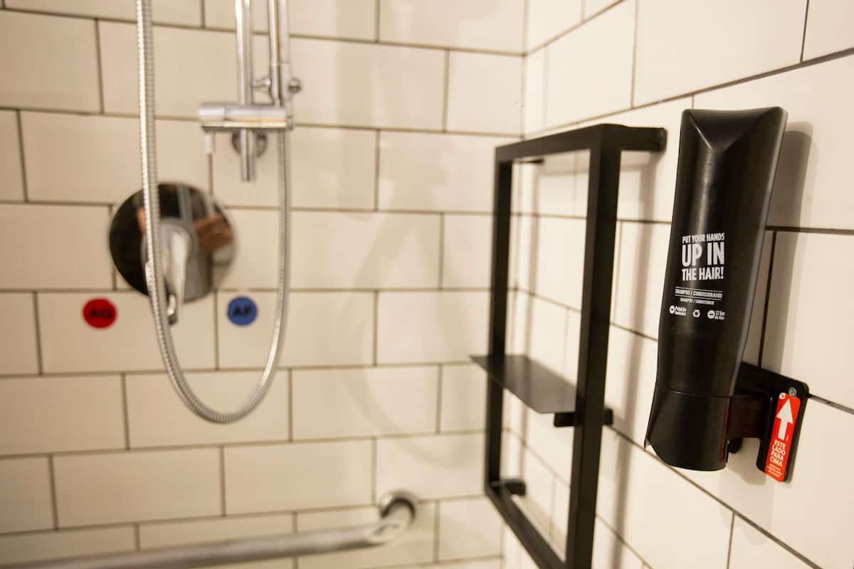 A bathroom with a shower, a towel rack, and a shampoo bottle.