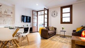 A modern living room with a dining area, a large wall clock, and a cityscape mural. - Cozy duplex with Terrace, 1 Bedrooms, 2+2 Pax, Central Market, old town (Valencia)