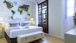 A modern bedroom with a world map mural, a large bed with a bench, wooden flooring, and a view through a glass door. - Cozy duplex with Terrace, 1 Bedrooms, 2+2 Pax, Central Market, old town (Valencia)