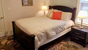 A bedroom with a bed, bedside tables, a lamp, a framed picture, and a decorative wall piece. - Cape Haven - Condo 1.5 Blocks from Beach (Cape Charles)
