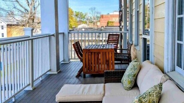A covered porch with wicker furniture, a glass coffee table, and a view of the neighborhood. - Cape Haven - Condo 1.5 Blocks from Beach (Cape Charles)