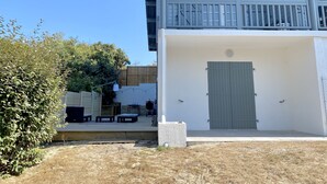 Un bâtiment à deux étages doté d’un balcon, d’une porte et d’un petit espace extérieur aménagé en coin salon.