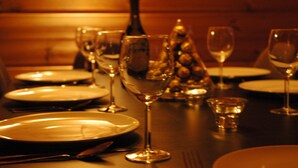 A dining table set with plates, glasses, and a bottle, likely in a restaurant or dining area. - Breathtaking Panoramic Alpine Views (Abondance)