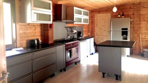 A kitchen with wooden walls and cabinets, a stove, and a refrigerator. - Breathtaking Panoramic Alpine Views (Abondance)