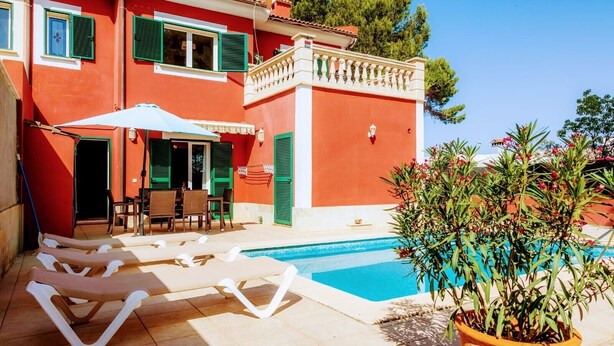 Un bâtiment rouge avec une piscine, des sièges en plein air et une plante en pot.