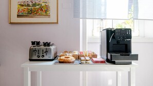 Una encimera de cocina con un tostador, una cafetera y varios productos de repostería.