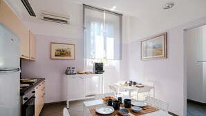 Una cocina moderna con armarios blancos, una estufa y un comedor con una mesa dispuesta para dos.