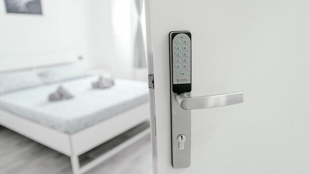 Un dormitorio moderno con cama, mesita de noche y cerradura electrónica en la pared.