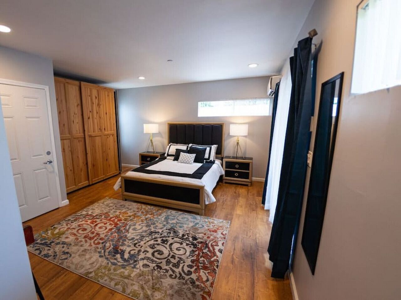 A bedroom with a bed, bedside tables, a wardrobe, and a patterned rug.