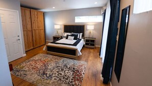 Ein Schlafzimmer mit einem Bett, Nachttischen, einem Kleiderschrank und einem gemusterten Teppich.