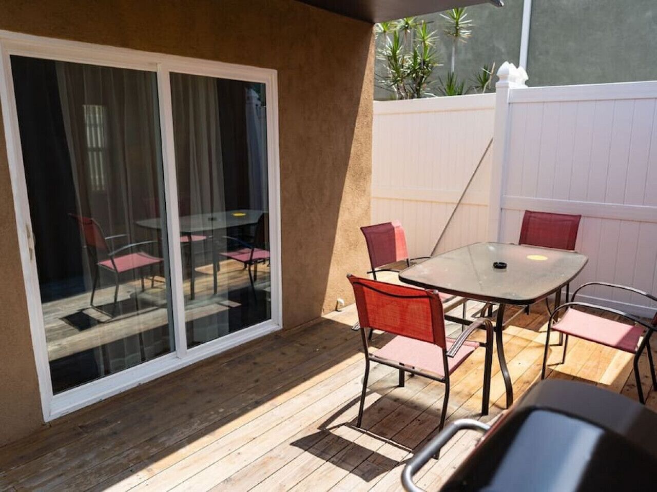 A patio with a table and chairs, a sliding glass door, and a wooden deck.