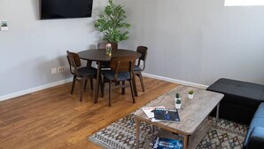 Ein Wohnzimmer mit Esstisch, Stühlen, Couchtisch, Fernseher und Klimaanlage.