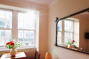 A room with a large window, a mirror, and two vases with flowers. - Bright Flat with Workspace in New Town (Edinburgh)