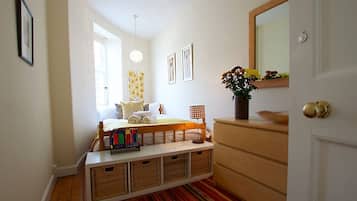 A bedroom with a bed, bedside tables, a dresser, a mirror, and a window.