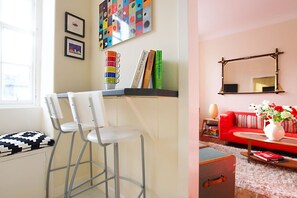 A room with a white desk, two white chairs, a red sofa, a mirror, and a colorful abstract painting on the wall. - Bright Flat with Workspace in New Town (Edinburgh)