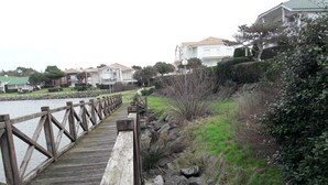 A wooden bridge leading to a residential area with houses and a body of water. - Large sea-facing studio with balcony and outdoor parkingeur 4 people (Saint-Jean-de-Monts)