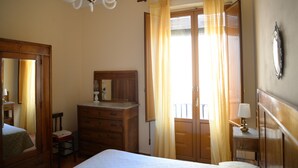A bedroom with a bed, wooden dresser, and a mirror. - Casa Naumachie Relax in a Safe and Wonderful Place (Taormina)