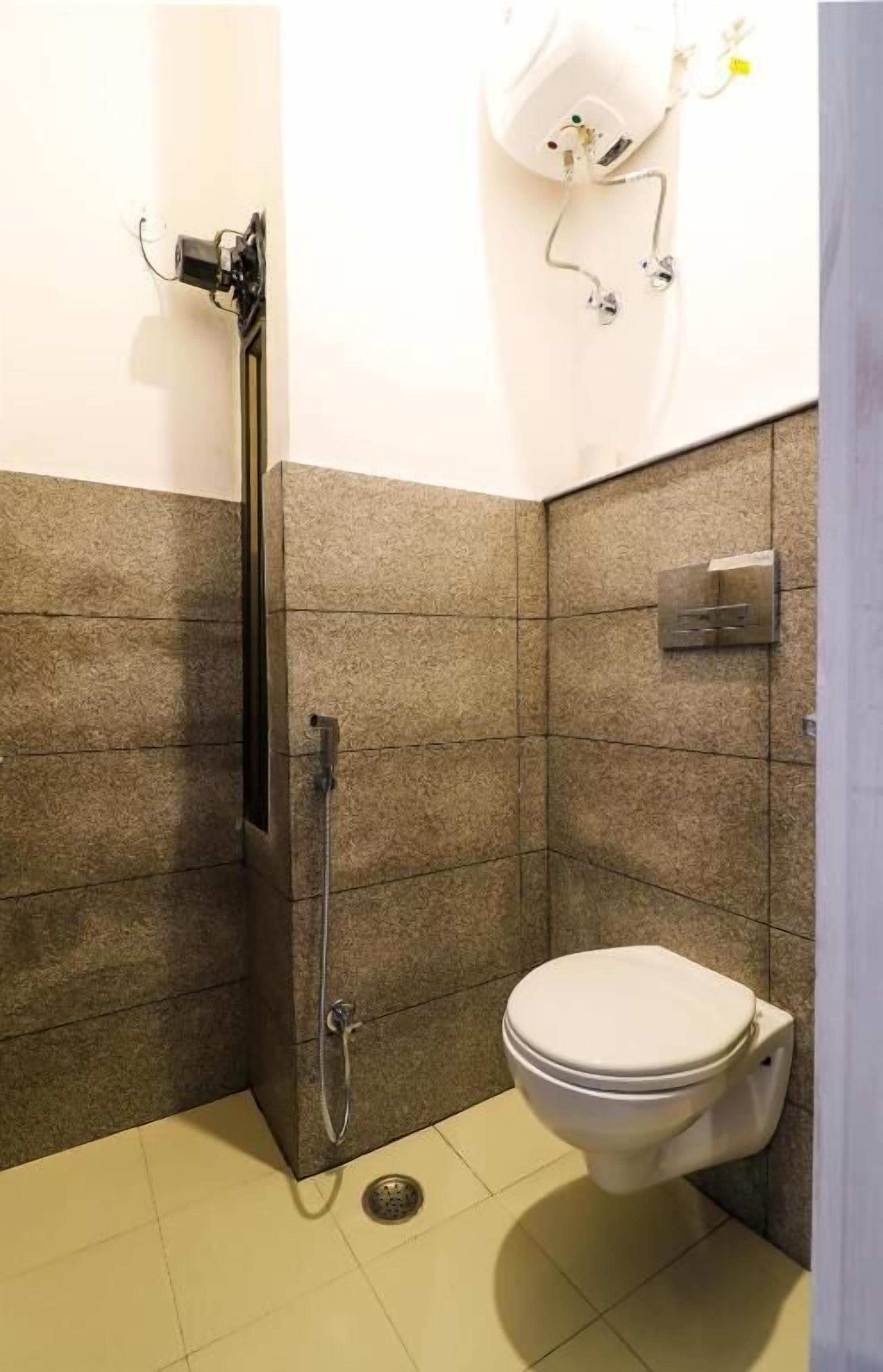 Een kleine badkamer met een douche, toilet en een zeepdispenser.