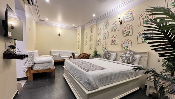 Un dormitorio con una cama grande, dos camas más pequeñas, un televisor y diseños decorativos en la pared.