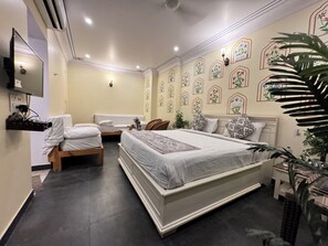 A bedroom with a large bed, two smaller beds, a TV, and decorative wall patterns.