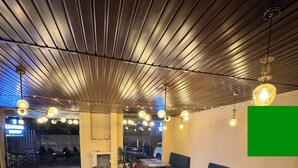 Un restaurante con mesas y sillas de madera, suelo con diseño y lámparas colgantes.