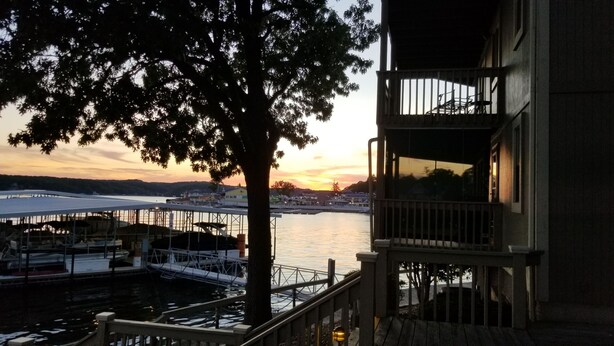 Ein Objekt direkt am Wasser mit einem Balkon, der auf eine Marina und einen Sonnenuntergang blickt.