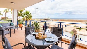 En balkon med et bord dækket til to, med udsigt over en strand.