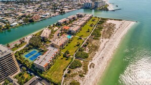 An aerial view of a coastal residential area with a marina, a tennis court, and a beach. - Land's End 204 building 5 Amazing Updates|Stunning views|Unique Floor Plan (Treasure Island)