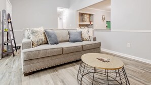Sala de estar com sofá, mesa de centro e escada.