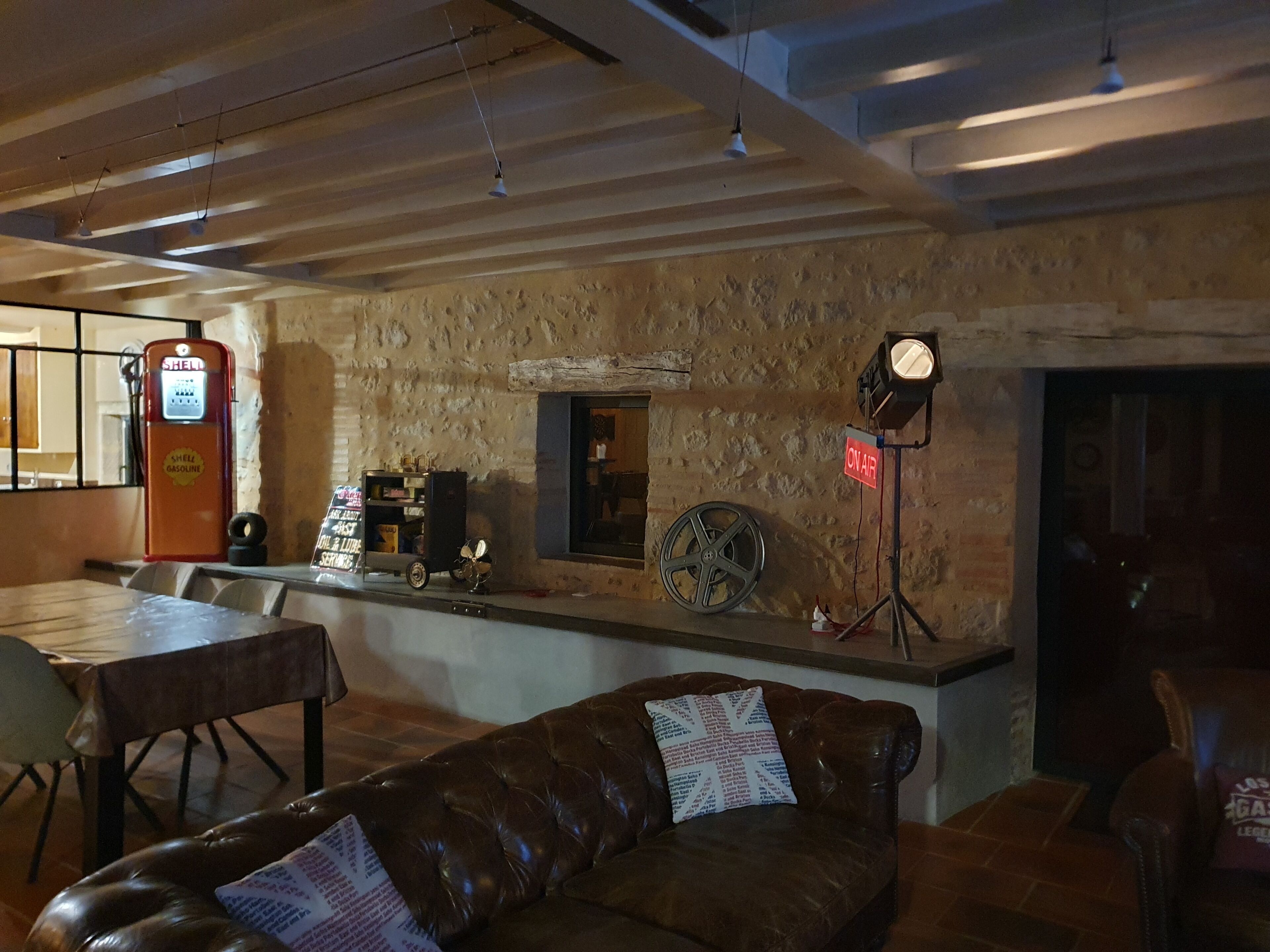A cozy bar area with a vintage gas pump, a motorcycle wheel, and a leather couch.
