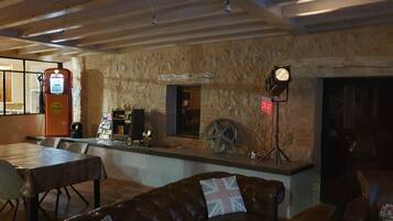 A cozy bar area with a vintage gas pump, a motorcycle wheel, and a leather couch.
