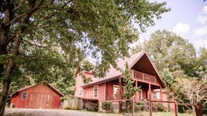 Ein rustikales Holzhaus mit Veranda und separater Garage, umgeben von Bäumen.