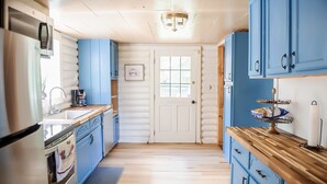 Eine Küche mit blauen Schränken, einer Holz Arbeitsplatte, einem Kühlschrank und einer Tür mit Fenster.