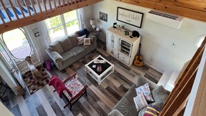 A spacious living room with a high ceiling, a staircase, a sofa, a coffee table, and a guitar. - Beautiful Family Retreat, Cavendish area. (Nous sommes bilingues) (Kensington)