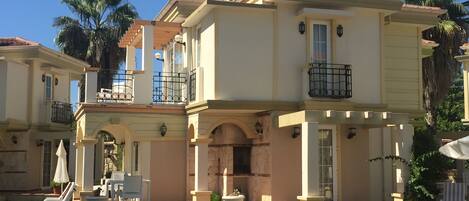 A two-story house with a balcony, a stone fireplace, and a well-maintained lawn.