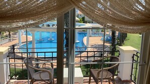Ein Balkon mit Korbstühlen und Blick auf einen Poolbereich.