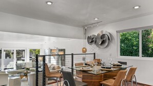 A modern dining area with a glass table, metal chairs, and a decorative wall piece.