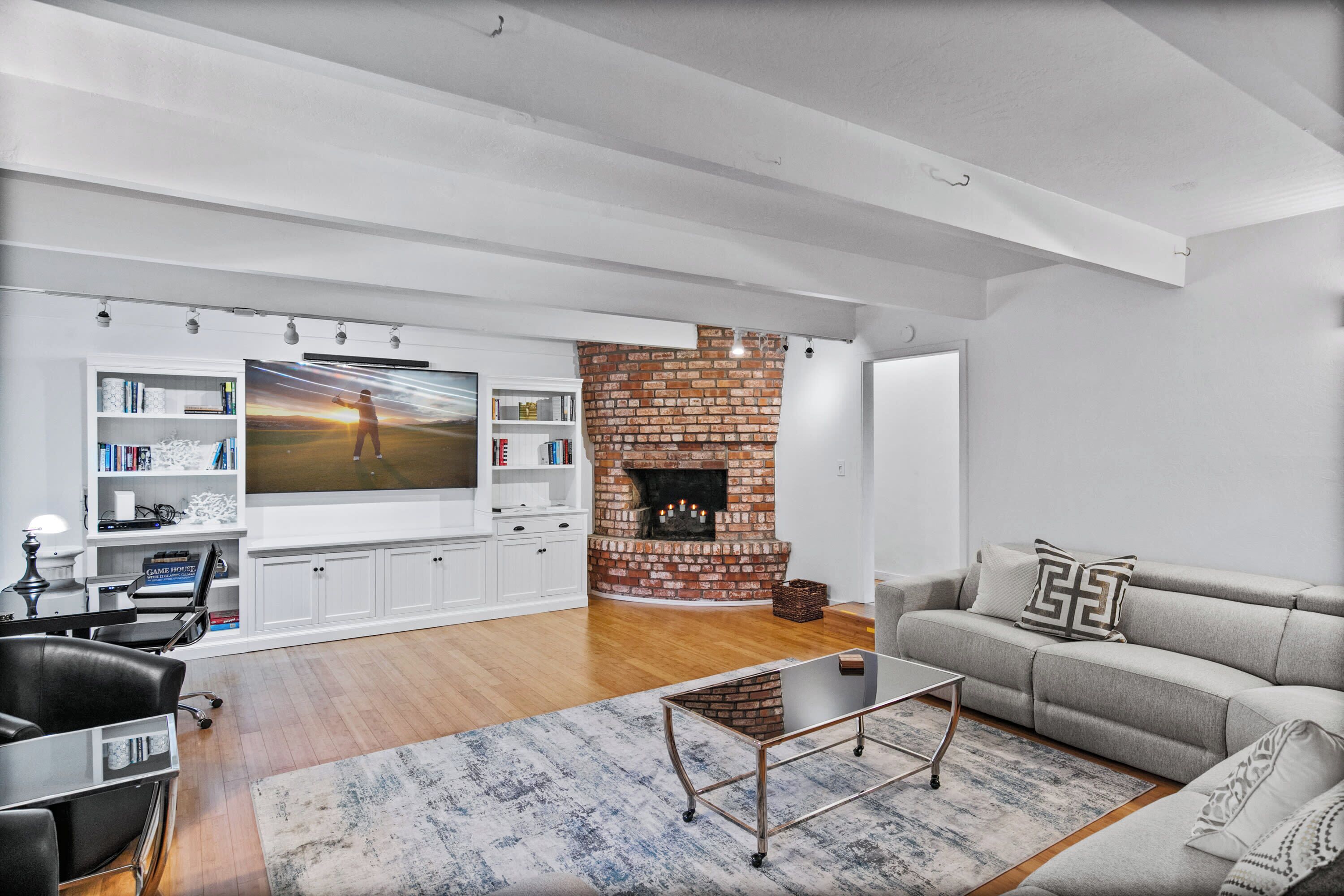 Een moderne woonkamer met een open haard, een grote flatscreen televisie, een bank en een salontafel.