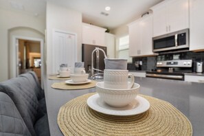 A modern kitchen with white cabinets, stainless steel appliances, and a central island with a woven placemat.