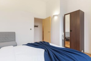 A bedroom with a bed, a wardrobe, and a door leading to another room.