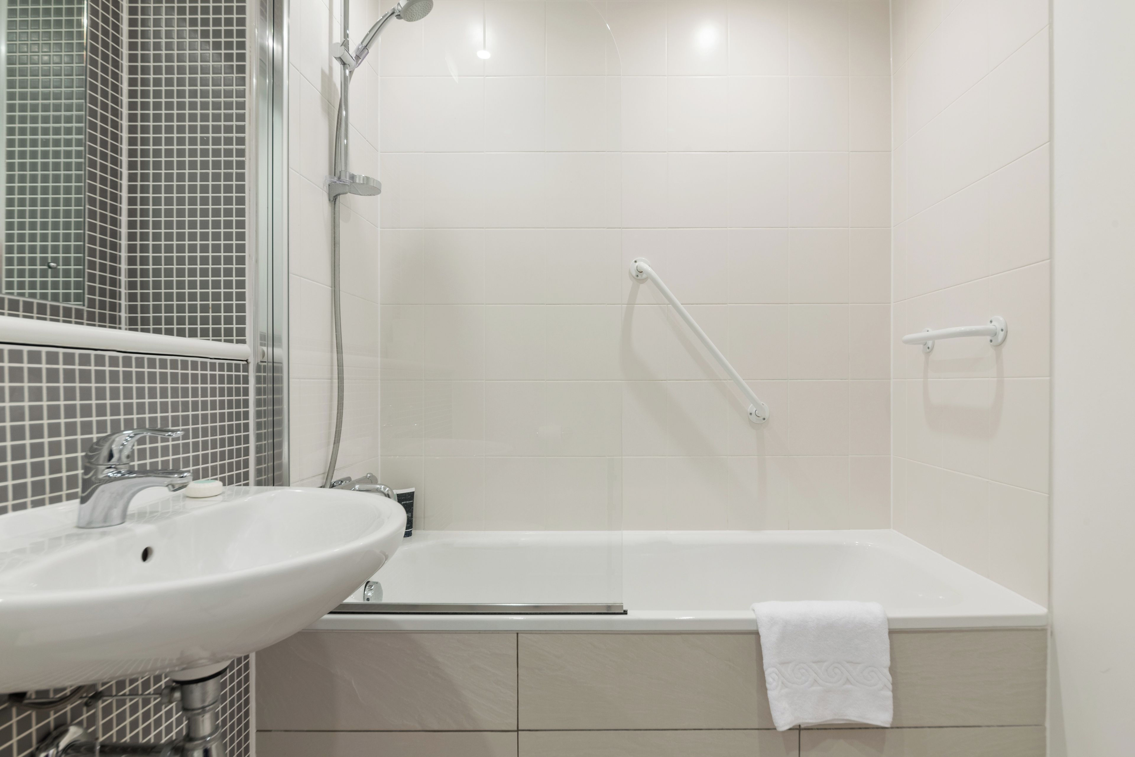 A bathroom with a white sink, a bathtub, and a shower area.