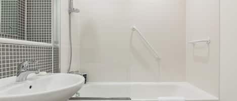 A bathroom with a white sink, a bathtub, and a shower area.
