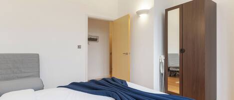 Ein Schlafzimmer mit einem Bett, einem Kleiderschrank und einer Tür zu einem anderen Raum.