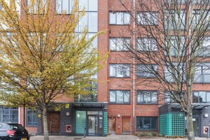 A multi-story building with a brick facade, large windows, and a gated entrance.