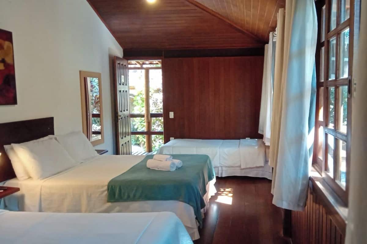 Ein Zimmer mit zwei Betten, Holzwänden und großen Fenstern mit Vorhängen.